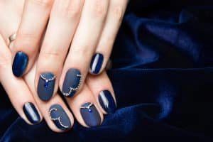 Beautiful manicured female hands with French manicure on dark blue background